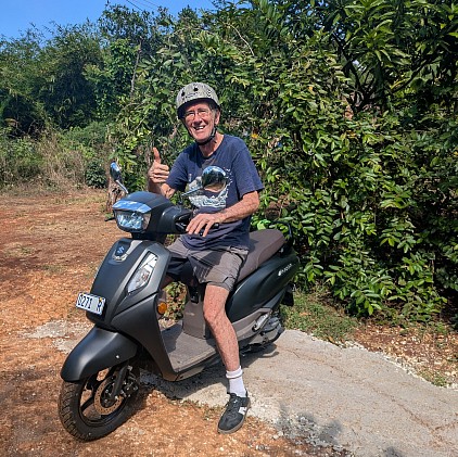 Older white male on a scooter with helmet and thumbs up